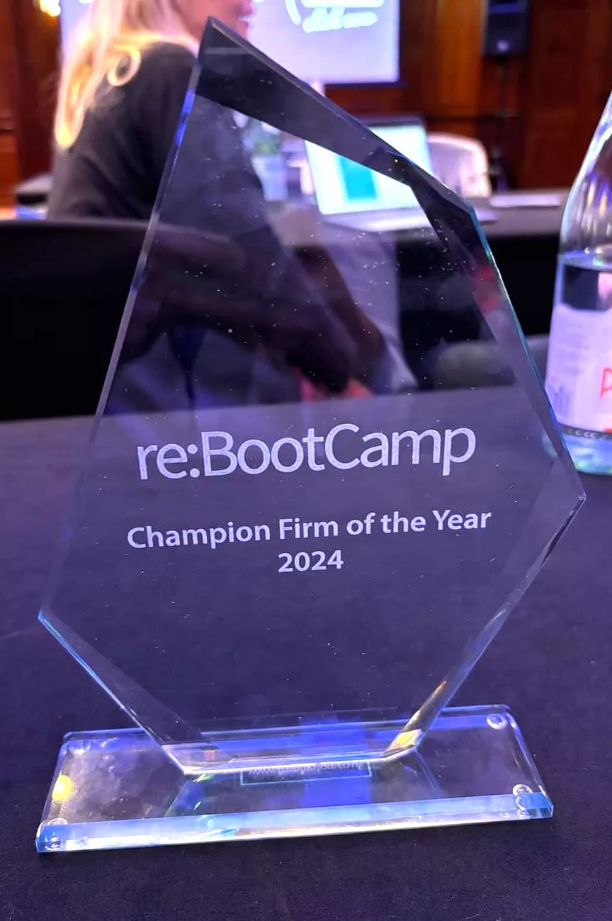 Picture of a glass award wth re:BootCamp Champion Firm of the Year 2024 engraved on, sat on a table.
