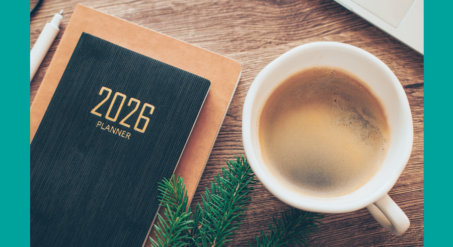 A cup of black coffee next to a 2026 diary on a desk, taken from above.
